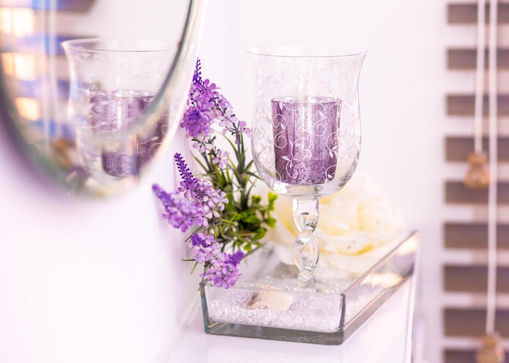 deux verres à vin et des fleurs violettes sur une table dans l'établissement Boutique Hotel ma maison, à Dömitz