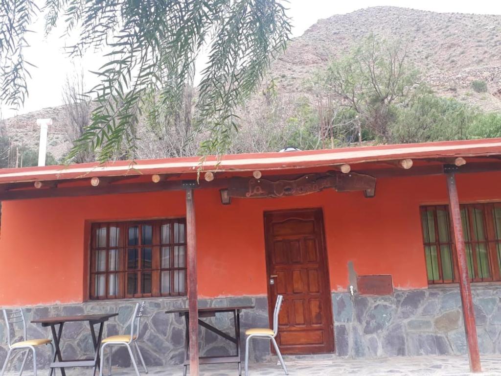 a red house with a table and chairs in front of it at La Posada de Bartola in Tilcara