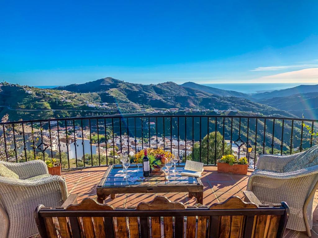 eine Holzterrasse mit einem Tisch und Stühlen auf dem Balkon in der Unterkunft Casa Madre Tierra con jacuzzi piscina zona de barbacoa y preciosas vistas in Cómpeta