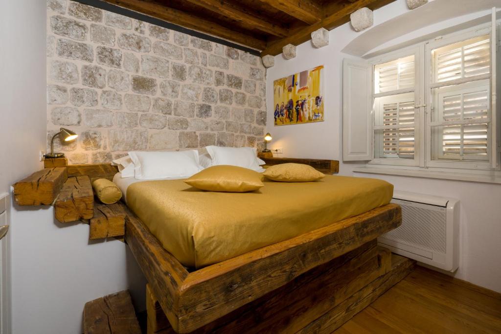 a bedroom with a bed and a stone wall at Nije Preša Apartments in Dubrovnik
