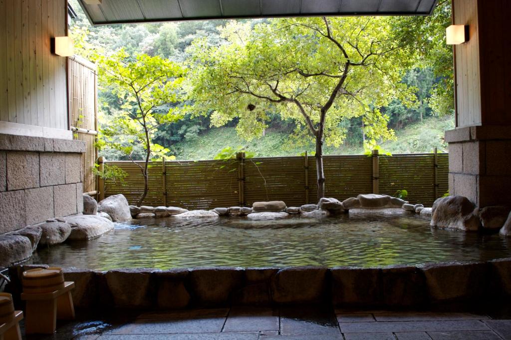 basen z wodą w budynku z drzewem w obiekcie Kawayu Onsen Fujiya w mieście Hongu
