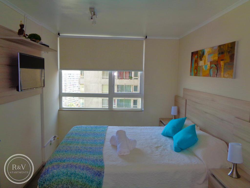 una camera da letto con un letto con cuscini blu e una finestra di R&V Apartments a Santiago