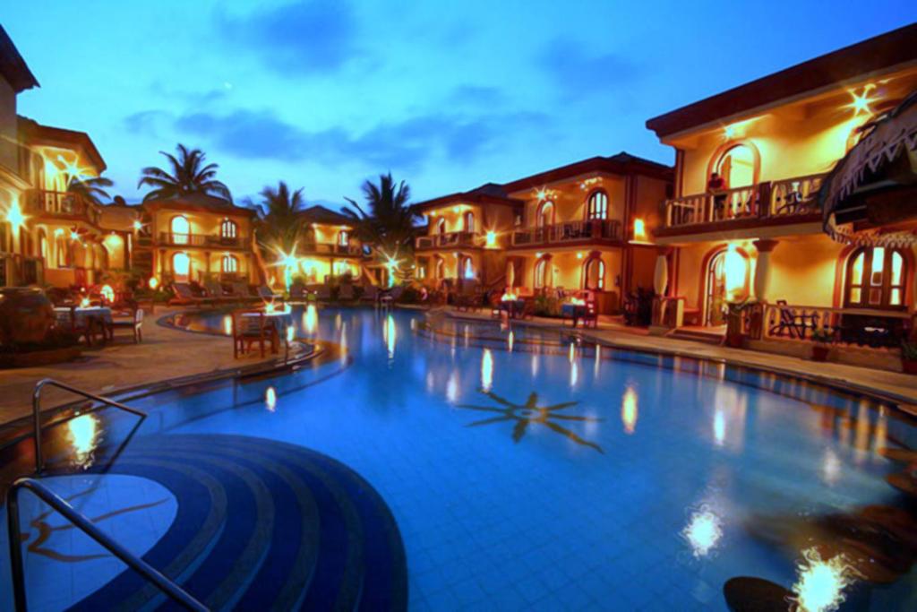 una grande piscina in un resort di notte di Resort Terra Paraiso a Calangute