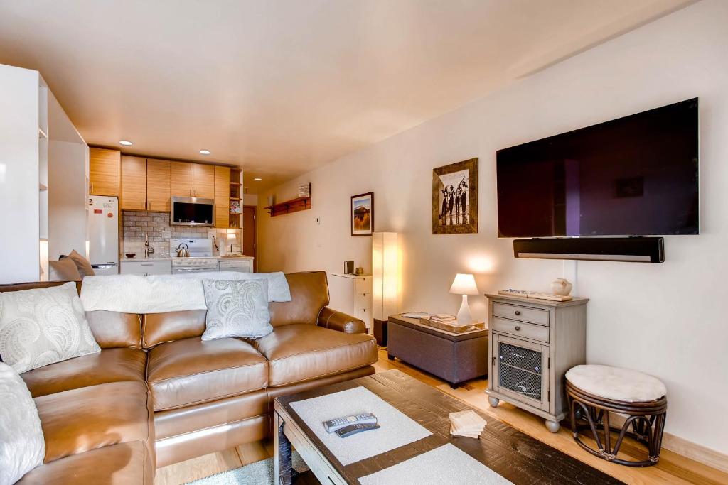 a living room with a leather couch and a kitchen at Cedar Lodge Peak One Studio Condo: Downtown Frisco in Frisco