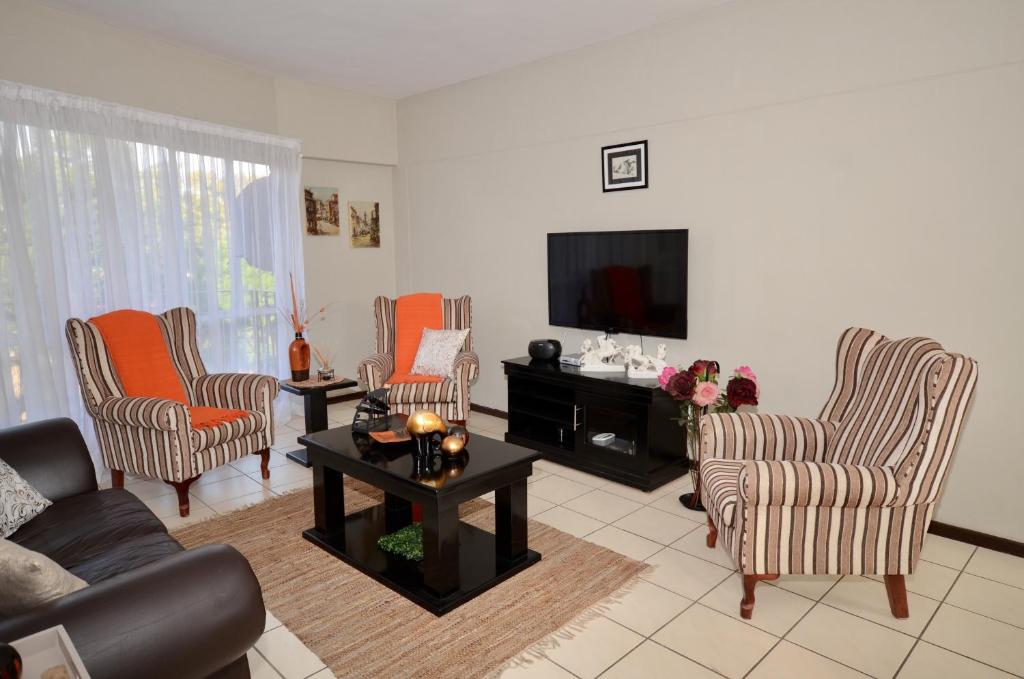 a living room with a couch and chairs and a tv at Libem Lodge 2 in Edenvale