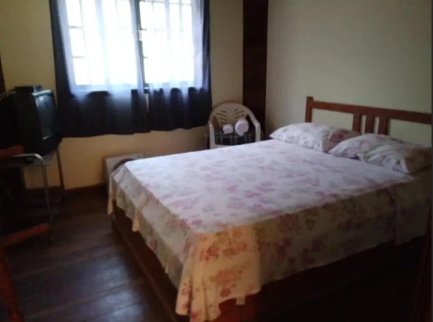 a bedroom with a bed and a television and a window at Hospedaria Tinoco in Ipiabas