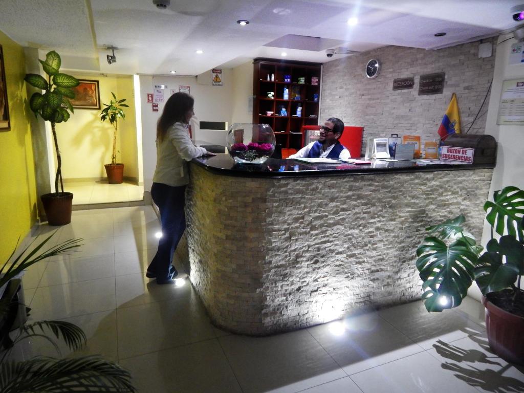 a woman standing at a bar in a restaurant at Hostal El Roble in Quito