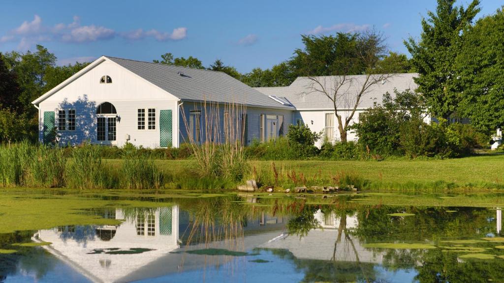 ein weißes Haus mit einem Teich davor in der Unterkunft Inntiquity, A Country Inn in Logansport