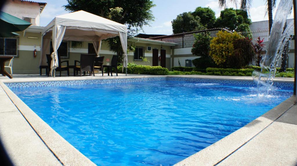 a swimming pool with a fountain in front of a house at Urdesa Suites Hotel in Guayaquil