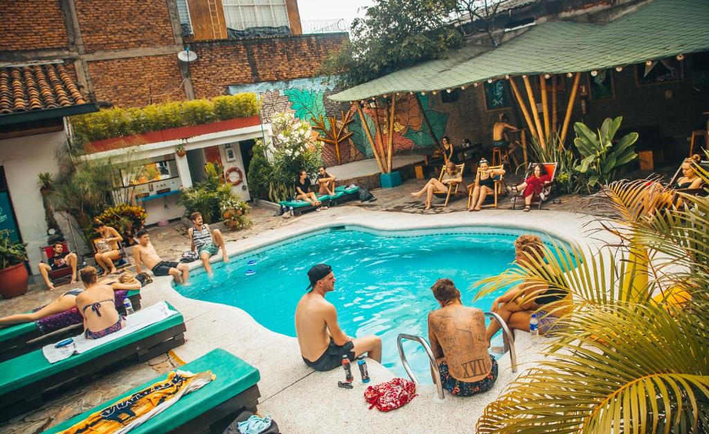 eine Gruppe von Menschen, die um einen Pool herum sitzen in der Unterkunft Viajero Hostel Cali & Salsa School in Cali