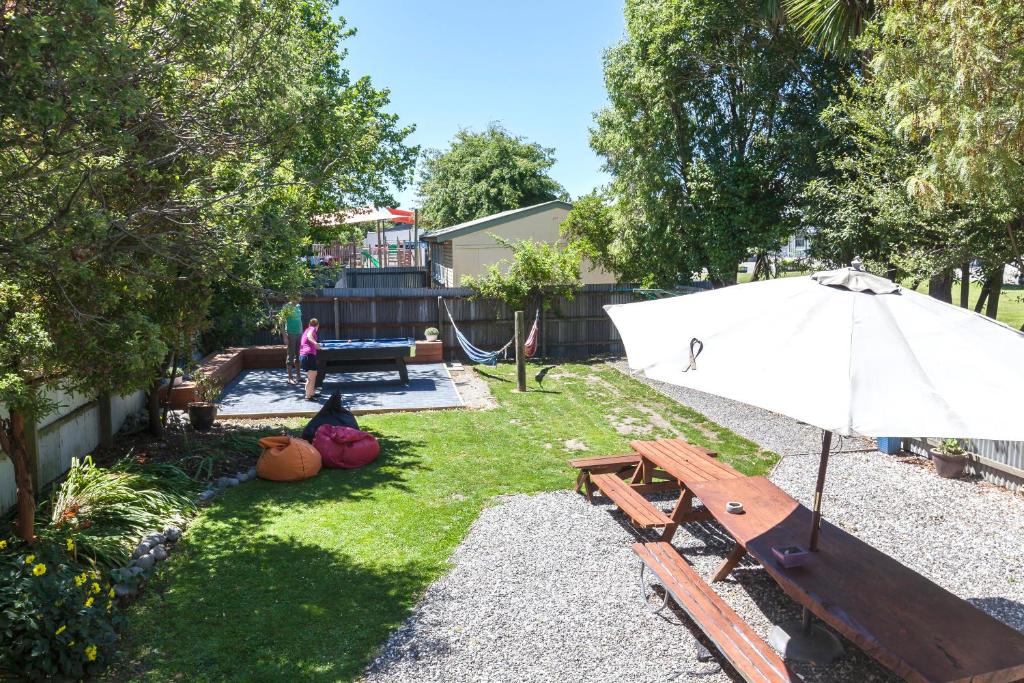 un patio trasero con una mesa de picnic y una sombrilla en Around The World Backpackers en Christchurch