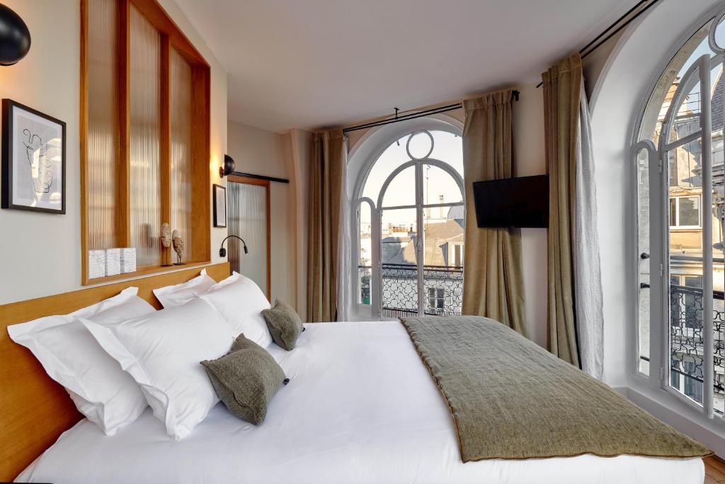 a bedroom with a white bed and a large window at Tinah Paris, Réaumur - Montorgeuil in Paris