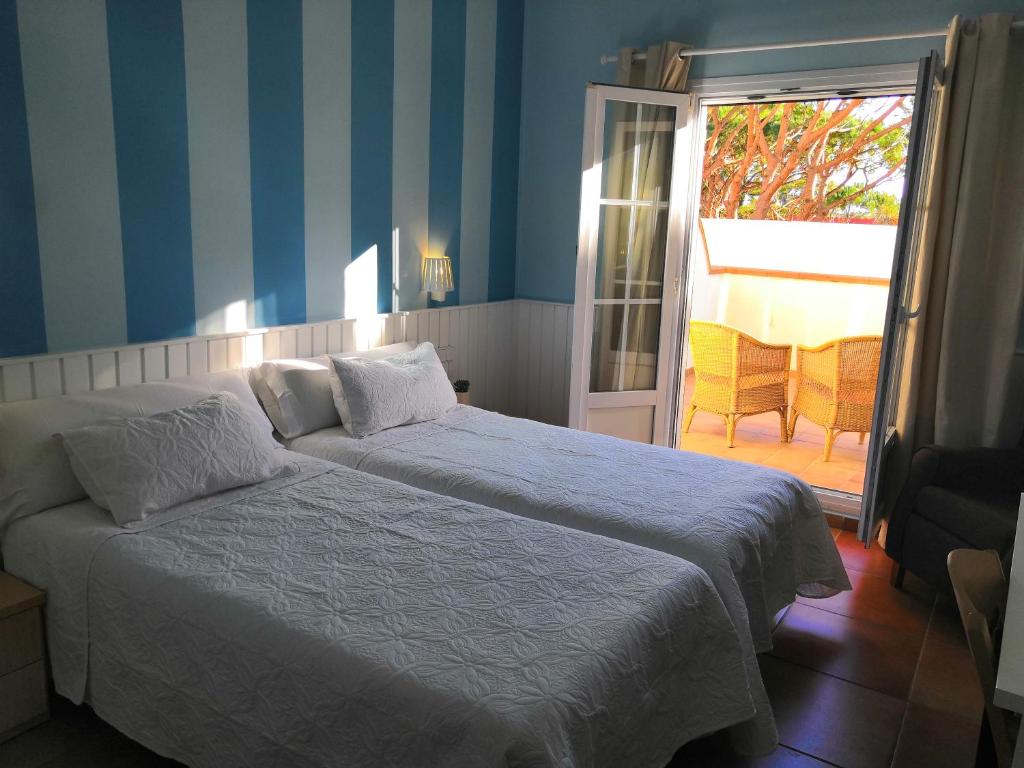 a bedroom with two beds and a door to a patio at Hotel Marisma Sancti Petri in Chiclana de la Frontera