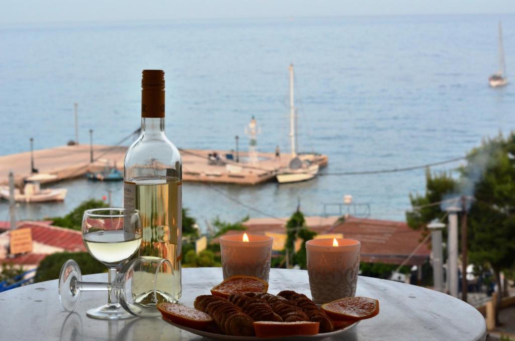 een fles wijn en een bord koekjes en een glas wijn bij Hotel Liberty 1 in Agia Marina Aegina