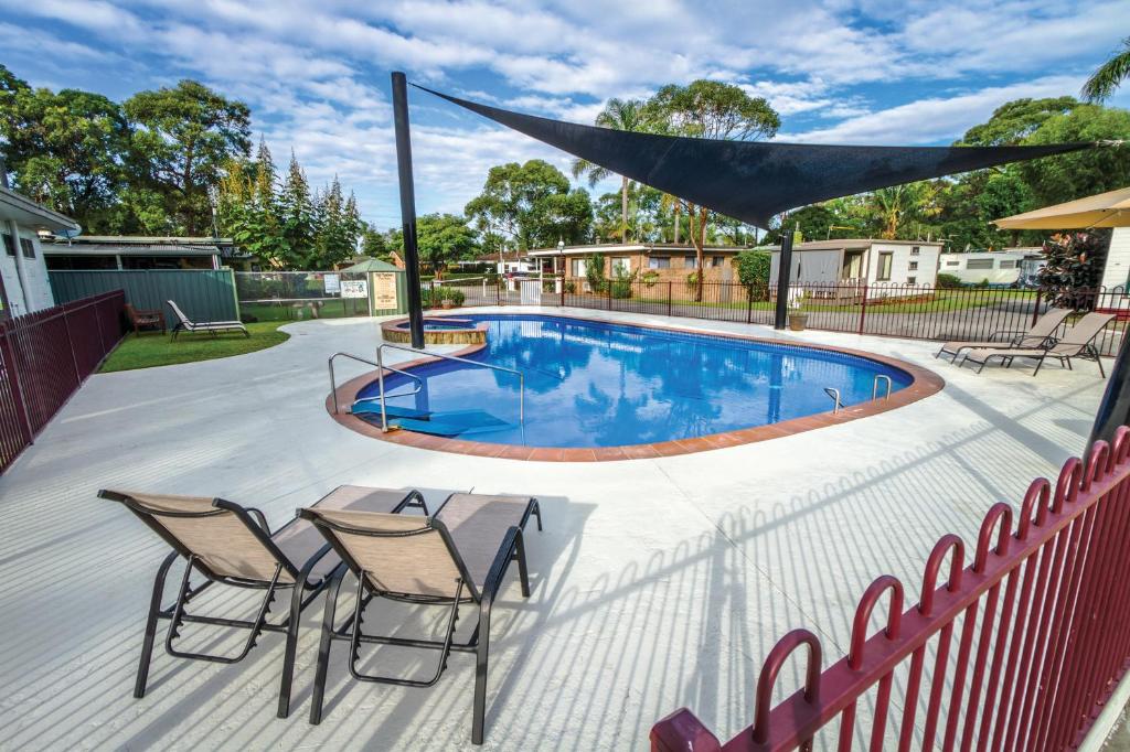 a swimming pool with two chairs and a table and a fence at Ingenia Holidays Shoalhaven Heads in Shoalhaven Heads