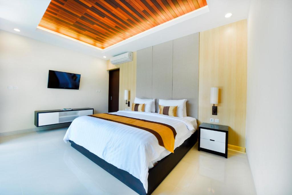 a bedroom with a large bed and a flat screen tv at La Paradis Villa in Canggu