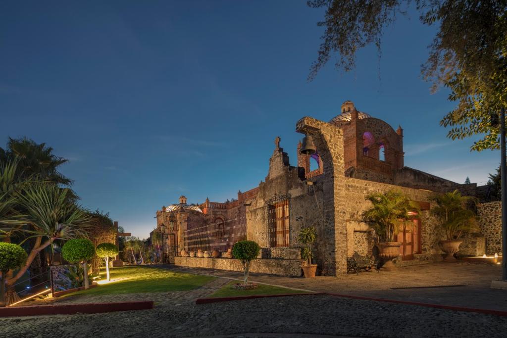 an old stone building with palm trees in front of it at Hacienda Santo Cristo Hotel & Spa - Adults Only in Atlixco
