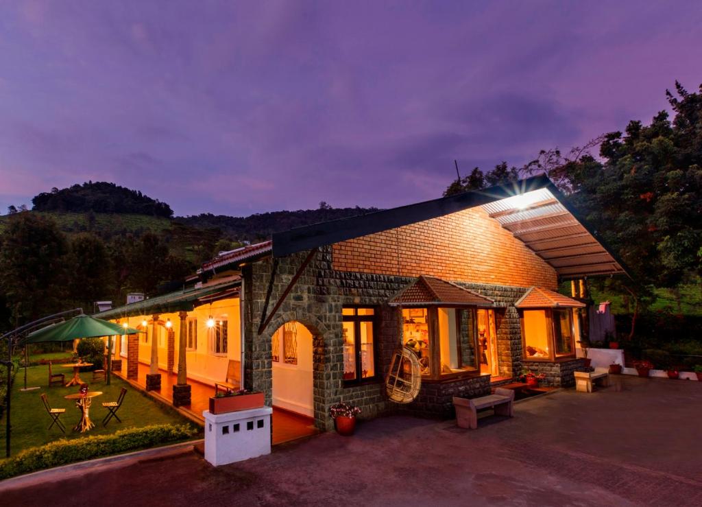 a house with a light on the side of it at Teanest by Nature Resorts in Coonoor