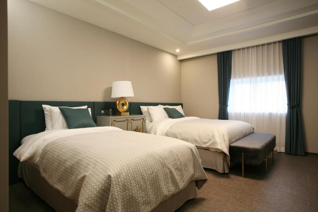 a hotel room with two beds and a window at Polaris Hotel in Bucheon