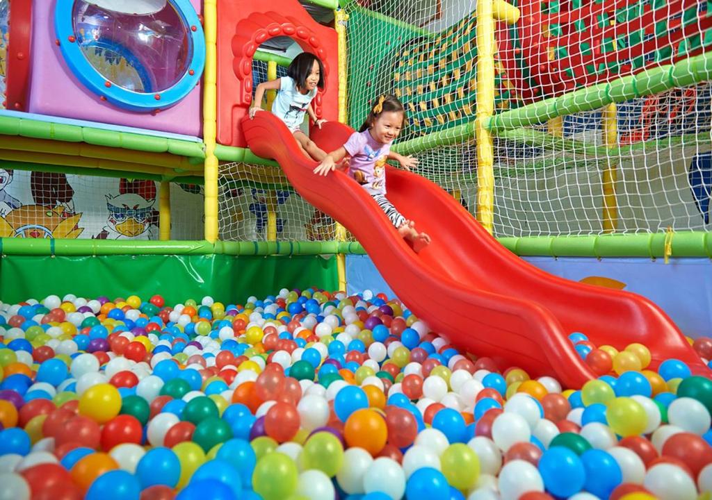 two young children playing on a slide in a ball pit at PARKROYAL Penang Resort in Batu Ferringhi