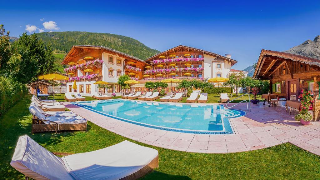 un complexe avec une piscine et un bâtiment dans l'établissement Alpenhotel Tirolerhof, à Neustift im Stubaital