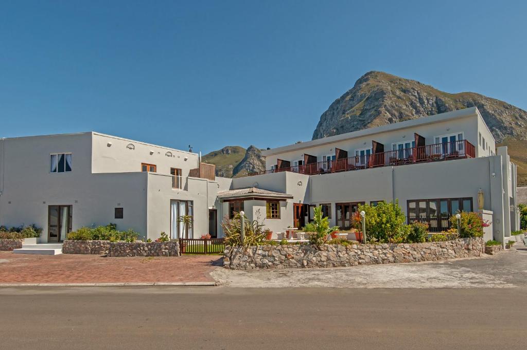 a large white building with a mountain in the background at Baleens Hotel in Hermanus