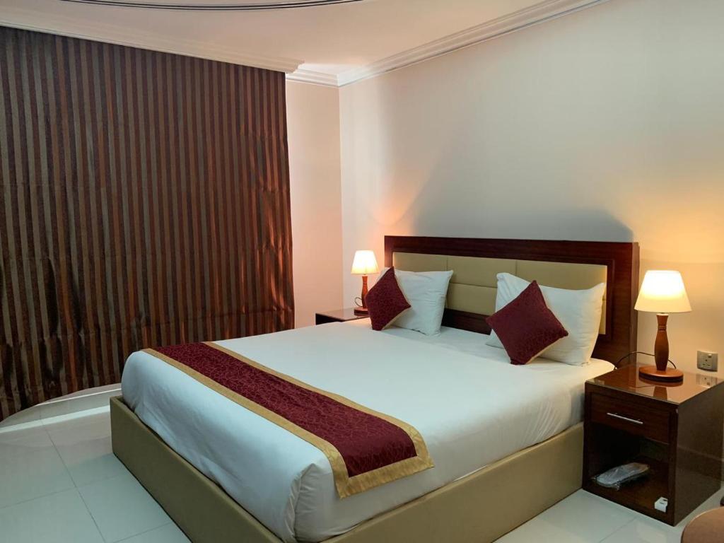a bedroom with a large white bed with red pillows at Hala Inn Hotel Apartments - BAITHANS in Ajman 