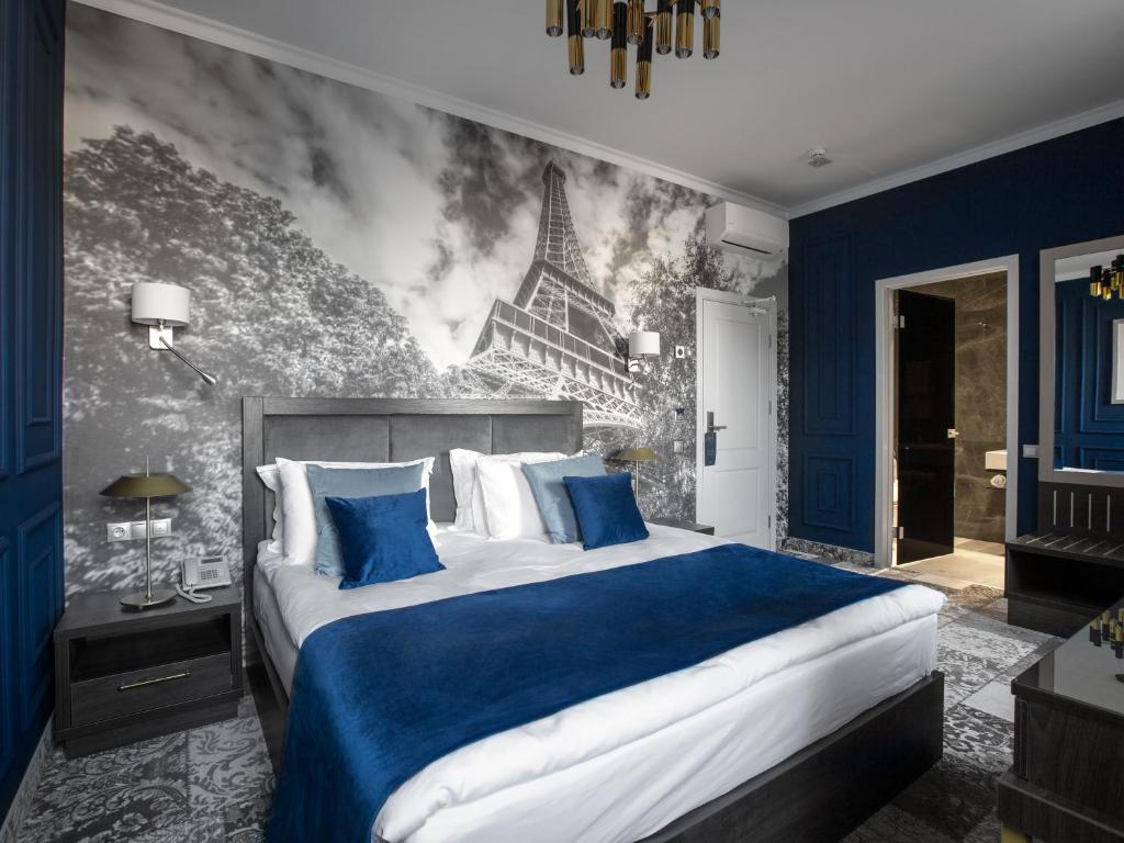 a bedroom with a king sized bed with a blue bedspread at Aquaperla Hotel & SPA in Chişinău