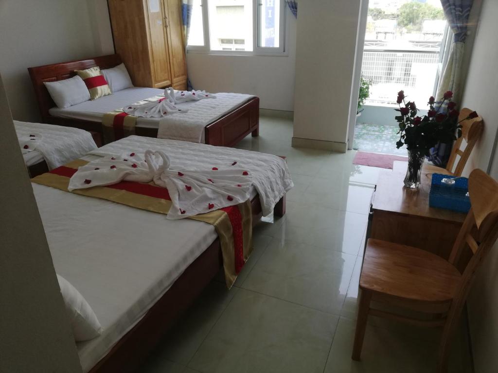 um quarto de hotel com duas camas e uma mesa e uma secretária em Hoang Kim Hotel em Vung Tau
