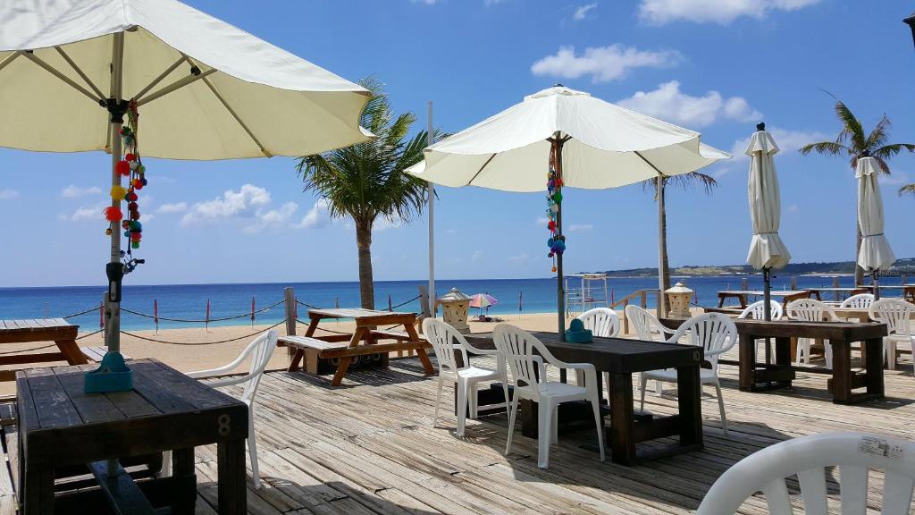 una terrazza in legno con tavoli e ombrelloni sulla spiaggia di 湛藍海岸民宿 Azure-零泊預約居-這個夏天有點藍--墾丁南灣沙灘-可包棟-國旅卡其他業別 a Nanwan