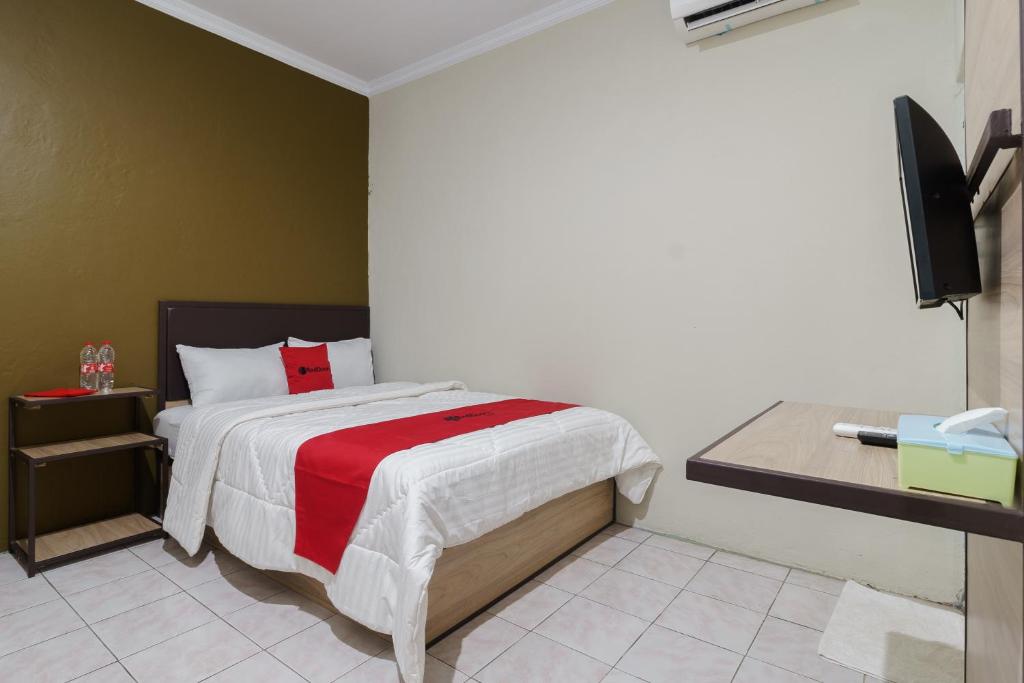 a bedroom with a bed with a red and white blanket at RedDoorz near Cikampek Mall Karawang in Karawang