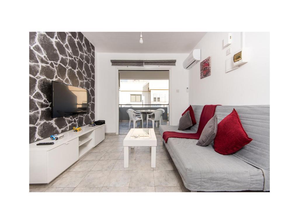 - un salon avec un canapé et une télévision dans l'établissement Holiday Apartment, à Larnaka