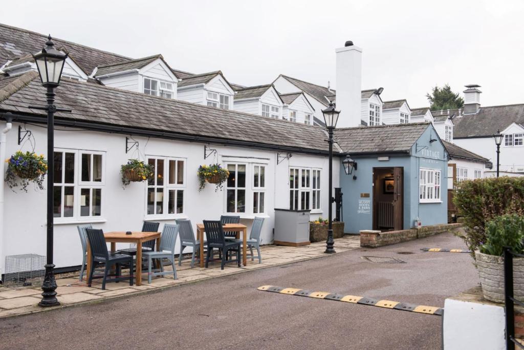 uma fila de casas brancas com mesas e cadeiras em The Five Bells by Innkeeper's Collection em Weston Turville