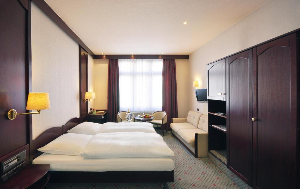 a hotel room with two beds and a couch at Hotel Imperial in Cologne