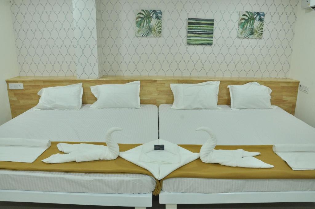 a white bed with two white towels on it at ADITI ROOMS in Tiruchchirāppalli