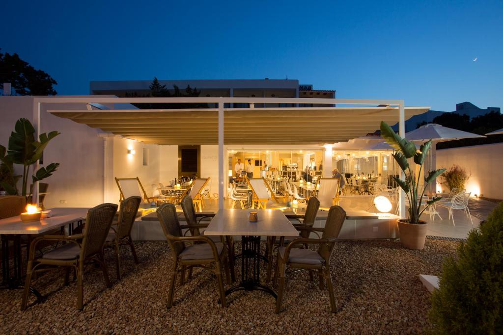a patio with tables and chairs and a building at Hotel Rosamar - Emar Hotels in Es Pujols