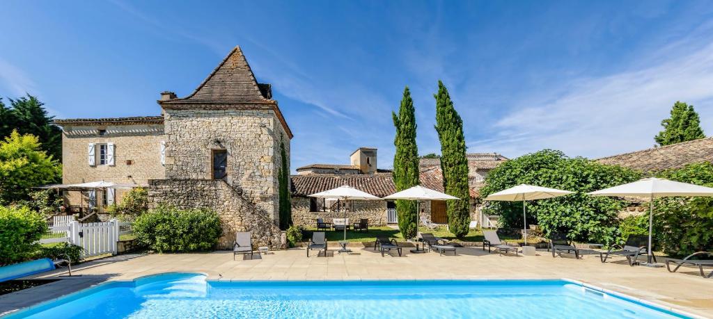 une piscine en face d'un bâtiment avec des parasols dans l'établissement Les Vents Bleus, à Donnazac