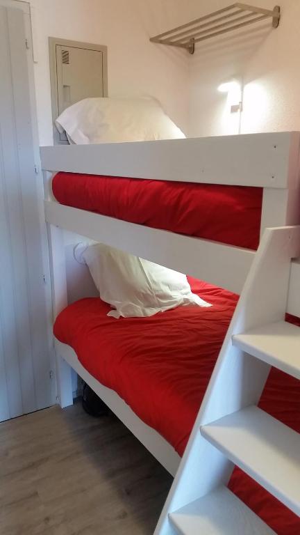 卡布勒通的住宿－Appartement Capbreton / Hossegor，一间卧室配有两张双层床,铺有红色床单