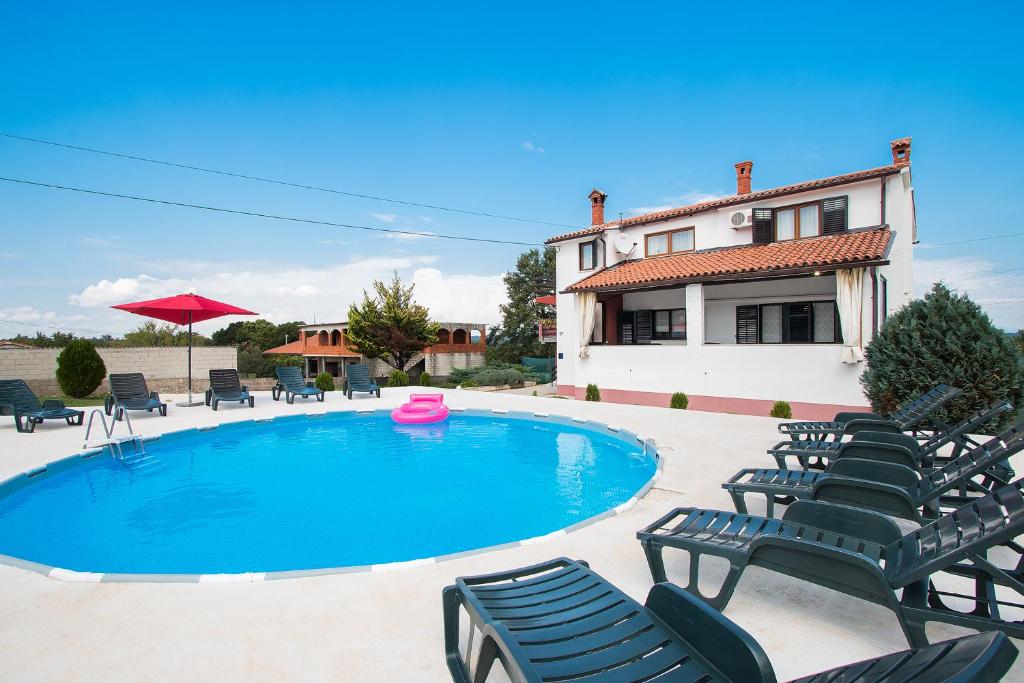 a pool with chairs and a pink frisbee next to a house at Apartments Skitača 1816 in Barban