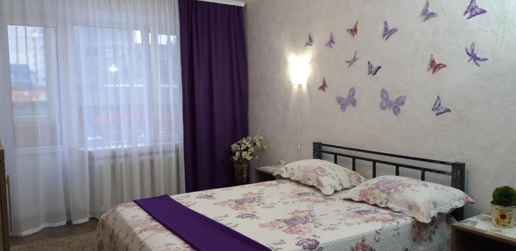 ein Schlafzimmer mit einem Bett mit Schmetterlingen an der Wand in der Unterkunft Apartment on Kamyanetskaya street in Chmelnyzkyj