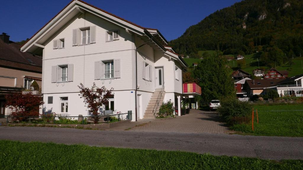 a white house with a hill in the background at Sandras Flat in Giswil