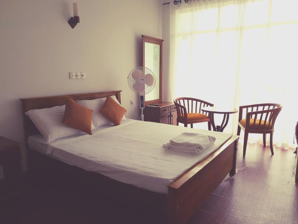 a bedroom with a bed with two chairs and a table at Medhani in Kandy