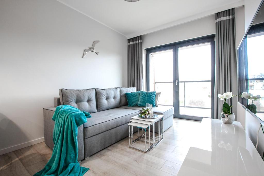 a living room with a gray couch with blue pillows at Apartamenty Studio Gardenia in Dziwnów
