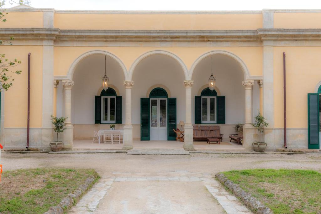 een gebouw met groene deuren en een patio bij Villa Giulio B&B DImora Storica in Santa Caterina di Nardò