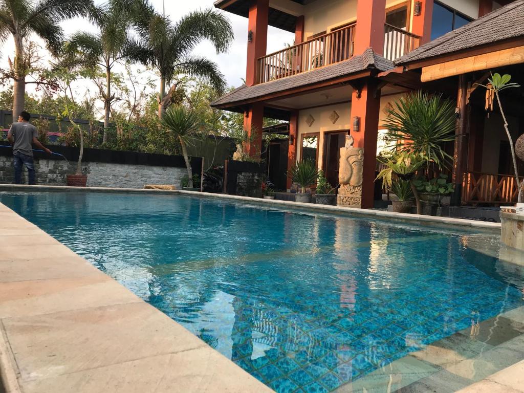a swimming pool in front of a house at Villa Kenanga in Meninting By The Beach in Mataram