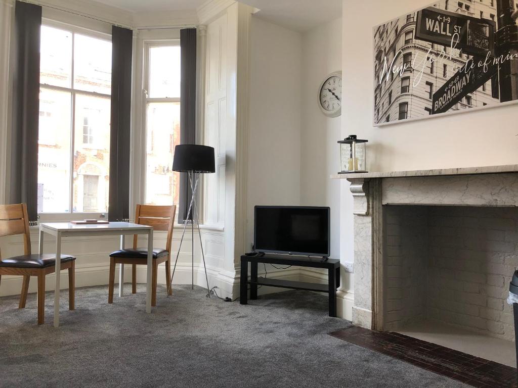 a living room with a fireplace and a table and a television at Fishergate ApartHotel 2 - City Centre Location in Preston