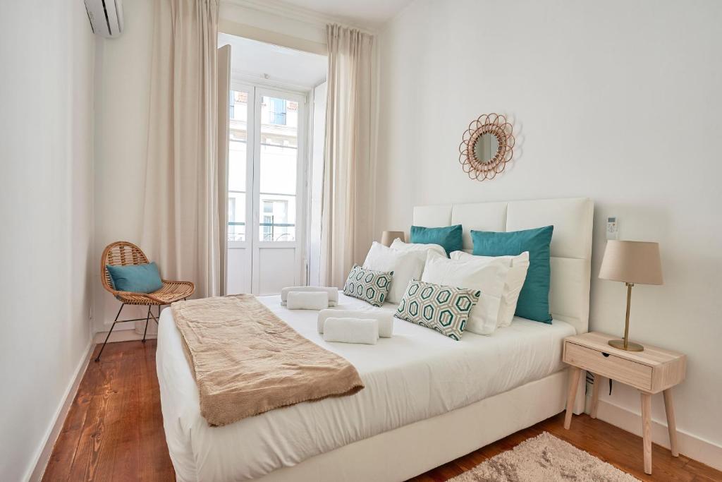 Casa Portuguesa Chiado 25 في لشبونة: غرفة نوم بيضاء مع سرير كبير مع وسائد زرقاء