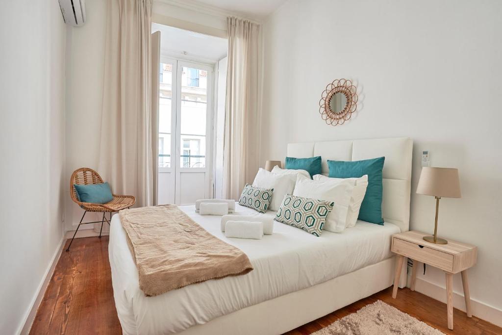 um quarto branco com uma cama grande e almofadas azuis em Casa Portuguesa Chiado 25 em Lisboa