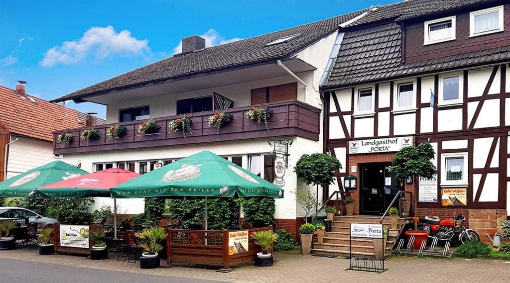 un bâtiment avec deux parasols devant lui dans l'établissement Landgasthof-Porta, à Üllershausen