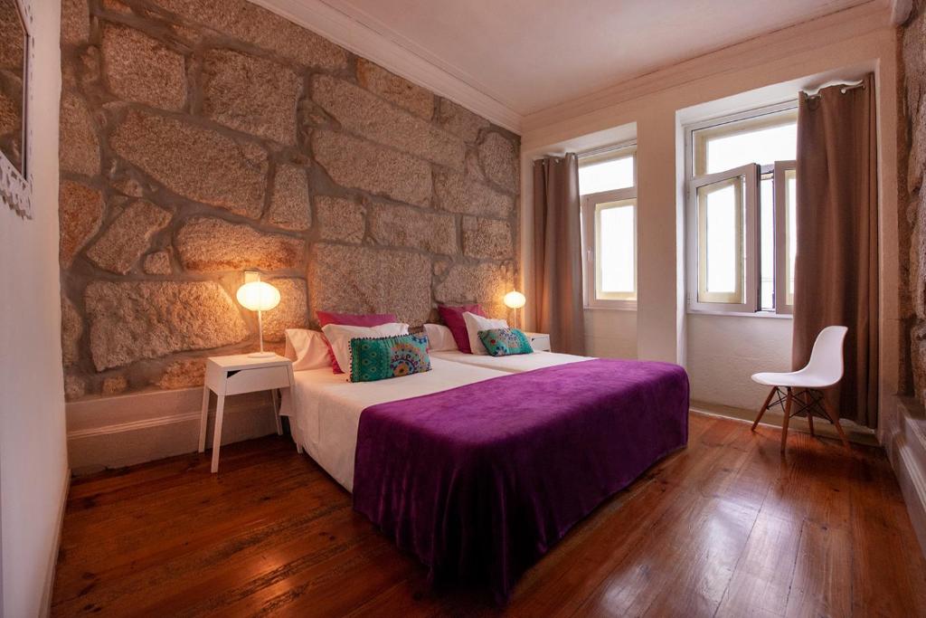 a bedroom with a large bed with a stone wall at OportoHouse in Porto